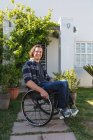 Porträt eines kaukasischen behinderten Mannes, der im Rollstuhl sitzt und im Garten lächelt. Behinderten- und Behindertenkonzept — Stockfoto