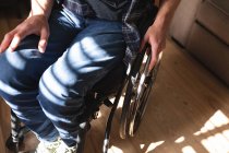 Sección media del hombre discapacitado sentado en silla de ruedas en casa. concepto de discapacidad y discapacidad - foto de stock