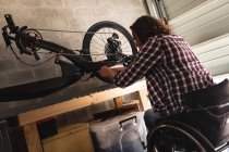 Caucasian disabled man sitting on wheelchair repairing another wheelchair at home. disability and handicap concept — Stock Photo
