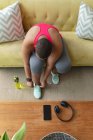 Африканский американец плюс женщина в спортивной одежде, сидящая на диване и завязывающая обувь. фитнес и здоровый, активный образ жизни. — стоковое фото