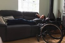 Белый инвалид дремлет дома на диване. Концепция инвалидности и инвалидности — стоковое фото