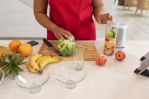 Midsection de mulher plus size preparando smoothie na cozinha. estilo de vida saudável, cozinhar e passar o tempo em casa. — Fotografia de Stock
