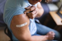 Partie médiane d'un homme handicapé caucasien montrant son épaule vaccinée à la maison. vaccination pour la prévention de l'éclosion de coronavirus concept — Photo de stock