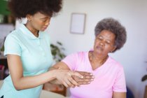 Африканська американська жінка-фізіотерапевт лікує руки старшої жінки-пацієнта в клініці. Вища медична допомога та фізіотерапія. — стокове фото