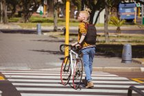 Thoughtful albino african american man with dreadlocks crossing road bike. on the go, out and about in the city. — Stock Photo