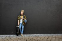 Pensativo albino homem americano africano com dreadlocks segurando skate usando smartphone. nômade digital em movimento, para fora e sobre na cidade. — Fotografia de Stock