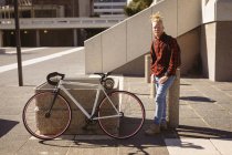 Portrait de souriant homme afro-américain albinos avec dreadlocks dans la rue avec vélo. on the go, out and about dans la ville. — Photo de stock