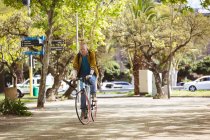 Pensiero albino uomo afroamericano con dreadlocks in sella alla bicicletta. in movimento, in giro per la città. — Foto stock