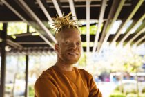 Ritratto di sorridente uomo afroamericano albino con dreadlocks che guarda la macchina fotografica. in movimento, in giro per la città. — Foto stock