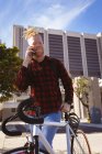 Retrato sonriente albino hombre afroamericano con rastas en el parque con bicicleta hablando en el teléfono inteligente. nómada digital sobre la marcha, fuera y alrededor de la ciudad. - foto de stock