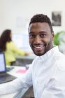 Porträt eines lächelnden afrikanisch-amerikanischen Geschäftsmannes, der in einem modernen Büro in die Kamera blickt. Geschäfts- und Büroarbeitsplätze. — Stockfoto