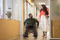 Афріканський бізнесмен в інвалідному візку розмовляє з білоруською діловою жінкою в сучасному офісі. на роботі та в офісі. — стокове фото