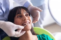 Кавказский стоматолог-мужчина осматривает зубы пациентки в современной стоматологической клинике. здравоохранение и стоматология. — стоковое фото