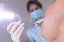 Кавказька стоматологічна медсестра вивчає зуби пацієнта чоловічої статі в сучасній стоматологічній клініці. Медичне обслуговування та стоматологія. — стокове фото