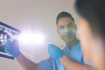 Sonriente dentista masculino caucásico sosteniendo lámpara examinando paciente femenina en clínica dental moderna. negocio de salud y odontología. - foto de stock