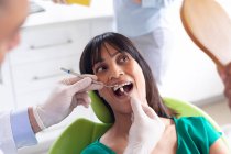 Odontoiatra caucasica che esamina i denti di una paziente in una moderna clinica dentistica. attività sanitaria e odontoiatrica. — Foto stock