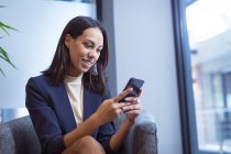 Двухсторонняя деловая женщина улыбается и разговаривает по смартфону, сидит в современном офисе. деловые и офисные рабочие места. — стоковое фото