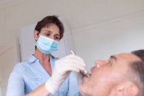 Kaukasische Zahnpflegerin untersucht die Zähne eines männlichen Patienten in einer modernen Zahnklinik. Gesundheits- und Zahnarztgeschäft. — Stockfoto
