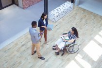 Two diverse business people talking with disabled female colleague in modern office. business and office workplace. — Stock Photo