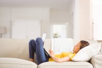 Glückliche Asiatin auf dem Sofa liegend, daheim mit Laptop. Lifestyle und Entspannung zu Hause mit Technologie. — Stockfoto
