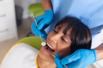 Dentista masculino caucasiano examinando dentes de paciente do sexo feminino na clínica odontológica moderna. serviços de saúde e odontologia. — Fotografia de Stock
