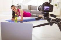 Счастливая азиатка упражняется на коврике, делая Фиттнес влог из дома. здоровый активный образ жизни и фитнес дома с технологиями. — стоковое фото