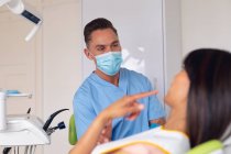 Кавказький чоловічий стоматолог у масках обличчя вивчає зуби пацієнтки в сучасній стоматологічній клініці. Медичне обслуговування та стоматологія. — стокове фото