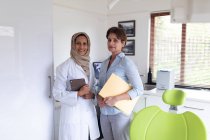 Ritratto di sorridente dentista femminile biennale e infermiera dentale femminile presso la moderna clinica dentale. attività sanitaria e odontoiatrica. — Foto stock