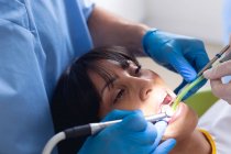 Кавказький самець-стоматолог і жінка-стоматолог, які вивчають зуби пацієнта в сучасній стоматологічній клініці. Медичне обслуговування та стоматологія. — стокове фото