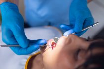 Dentista masculino caucásico examinando dientes de paciente femenina en clínica dental moderna. negocio de salud y odontología. - foto de stock