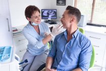 Lächelnde kaukasische Zahnpflegerin untersucht die Zähne eines männlichen Patienten in einer modernen Zahnklinik. Gesundheits- und Zahnarztgeschäft. — Stockfoto