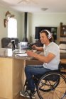Homme handicapé caucasien enregistrement podcast à l'aide d'un microphone assis à la maison. blogging, podcast et concept de technologie de radiodiffusion — Photo de stock