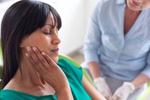 Patiente enceinte tenant son visage avec une infirmière dentaire caucasienne à la clinique dentaire moderne. soins de santé et de la dentisterie. — Photo de stock