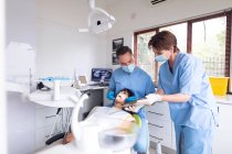 Kaukasischer Zahnarzt und Zahnpflegerin bei der Untersuchung der Zähne von Patienten in einer modernen Zahnklinik. Gesundheits- und Zahnarztgeschäft. — Stockfoto
