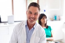 Portrait of smiling caucasian male dentist looking at camera at modern dental clinic. healthcare and dentistry business. — Stock Photo