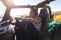 Homme caucasien réfléchi assis en voiture le jour ensoleillé au bord de la mer. road trip d'été et vacances dans la nature. — Photo de stock