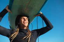 Surfista masculino feliz carregando prancha na cabeça contra o céu azul claro no dia ensolarado. hobbies e esporte aquático. — Fotografia de Stock