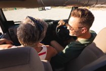 Feliz caucasiano gay masculino casal sentado no carro no ensolarado dia à beira-mar. viagem de verão e férias na natureza. — Fotografia de Stock