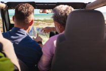 Kaukasisches schwules Paar liest Landkarte und sitzt im Auto am Meer. Sommer Roadtrip und Urlaub in der Natur. — Stockfoto