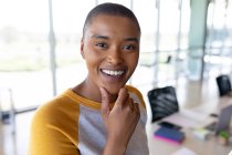Портрет улыбающейся африканской бизнесвумен с короткими волосами в креативном кабинете. креативный бизнес и офисное рабочее место. — стоковое фото
