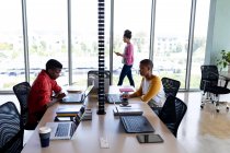 Африканські американські чоловіки і жінки-колеги працюють на ноутбуках за столом у творчому кабінеті. Творчий бізнес, бездротові технології та офісні роботи. — стокове фото