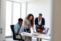 Multiracial male and female architects brainstorming over blueprint at desk in creative office. business, architect and creative office. — Stock Photo