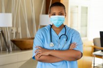 Портрет жінки-лікаря в масці, що стоїть з обіймами, схрещеними в лікарні під час ковад-19. медичні послуги та пандемія . — стокове фото