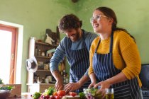 Glückliches junges Paar beim Kochen, während es in der Küche Gemüse hackt und mixt. häuslicher Lebensstil und Liebe, gesunde Ernährung. — Stockfoto