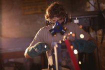 Blacksmith wearing gas mask while working on metal in manufacturing industry. forging, metalwork and manufacturing industry. — Stock Photo
