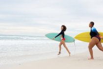 Unbekümmerte Freundinnen mit Surfbrettern, die am Wochenende am Strand laufen. Freundschaft, Surfen und Freizeit. — Stockfoto