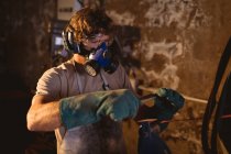 Blacksmith wearing gas mask while working on metal in industry. forging, metalwork and manufacturing industry. — Stock Photo