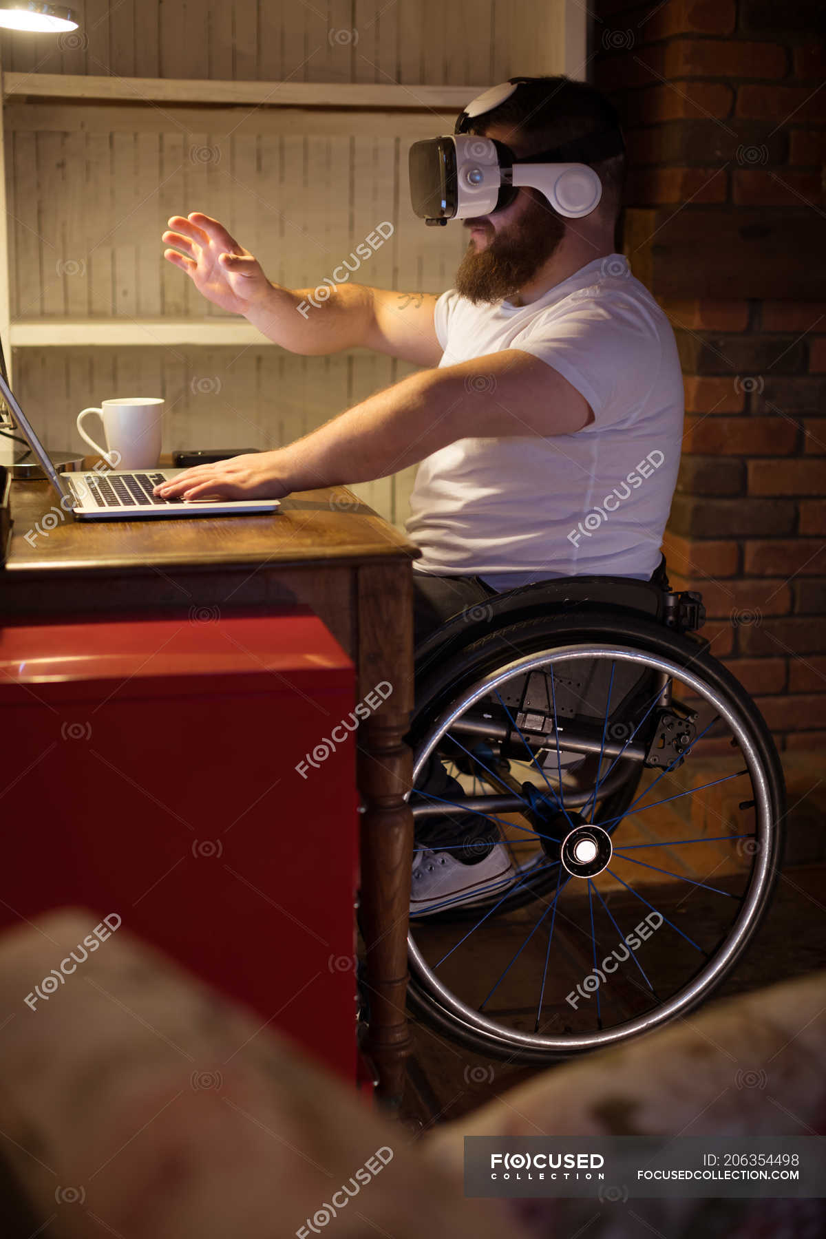 Disabled man in virtual reality headset using laptop at home — browsing, young adult Stock