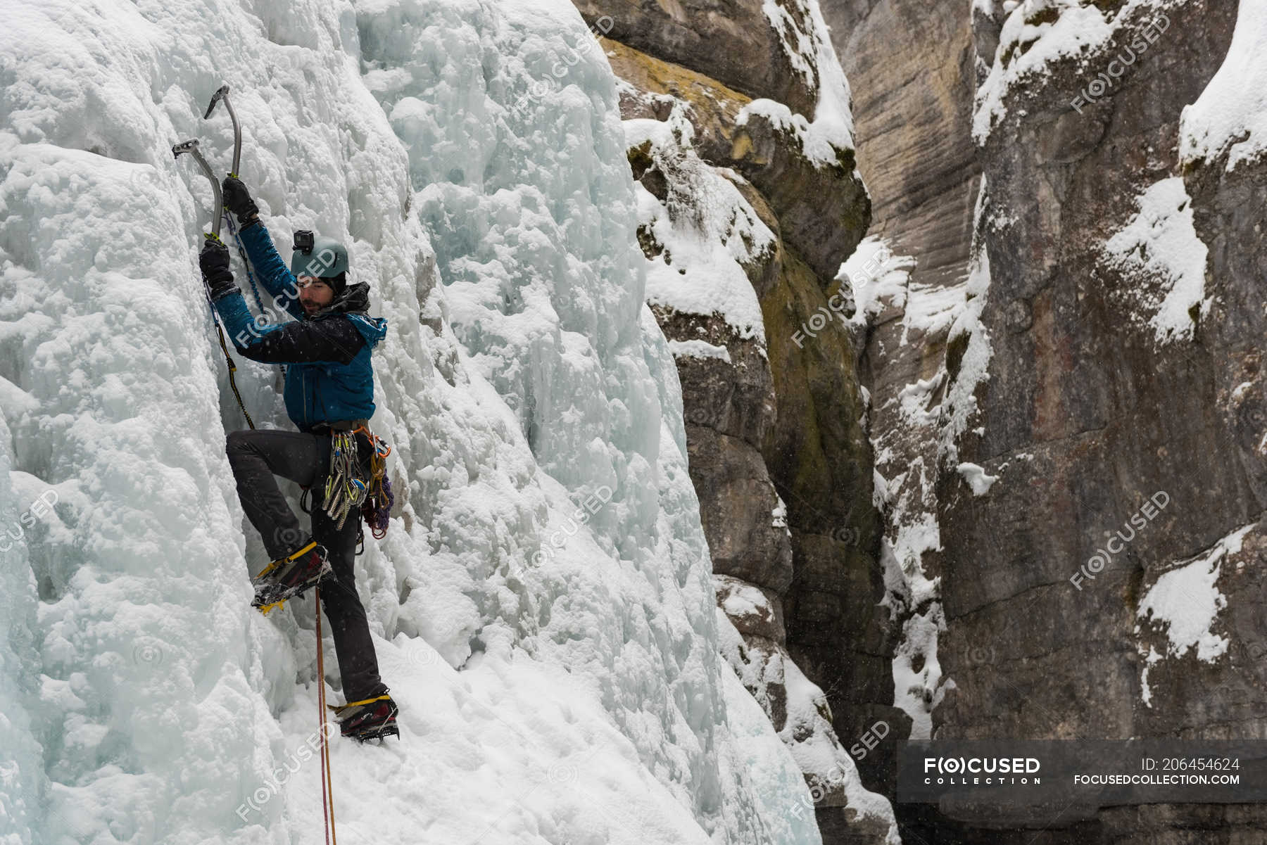 Male rock climber climbing ice mountain during winter — Revelstoke