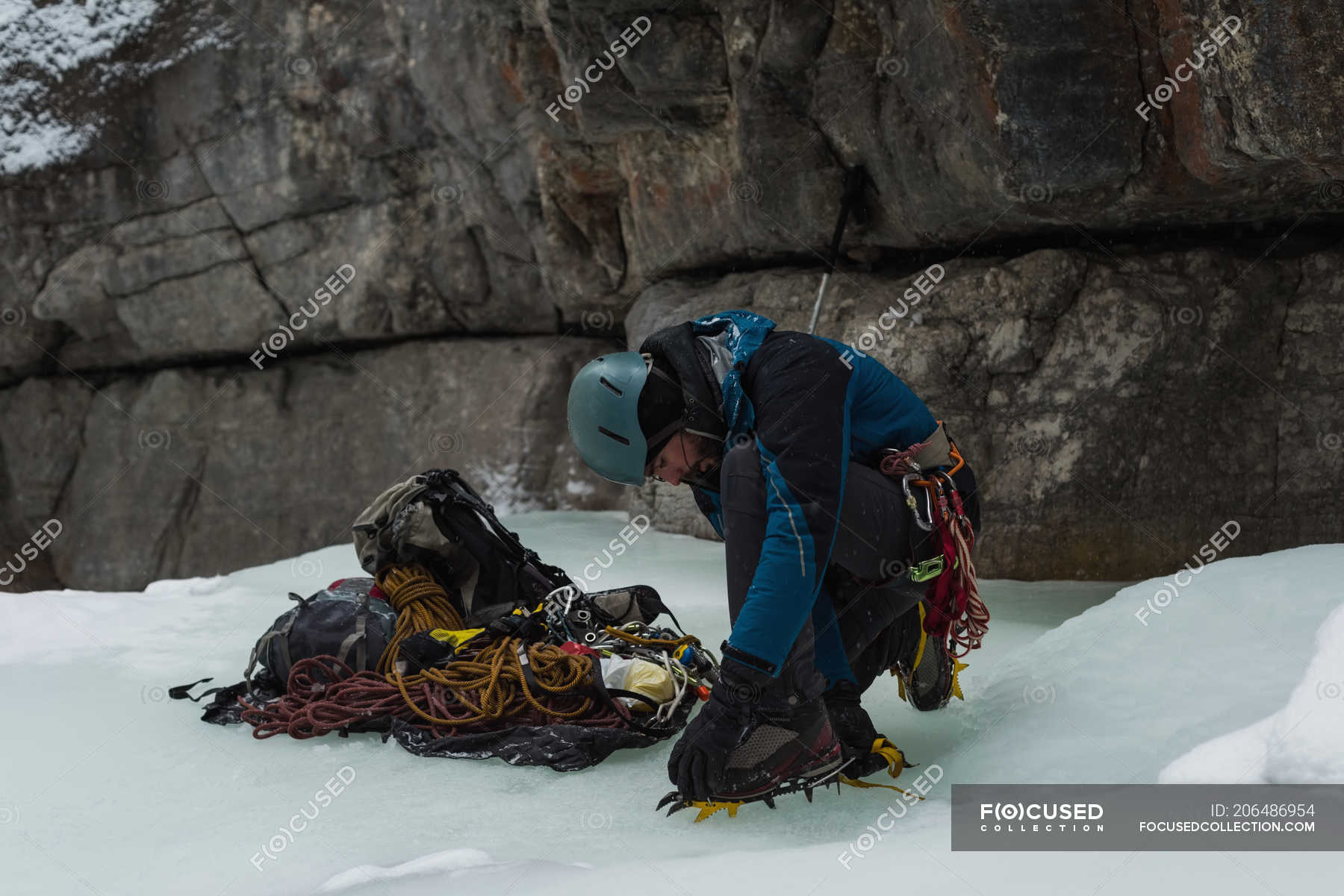 Male rock climber wearing crampons near rocky mountain during winter